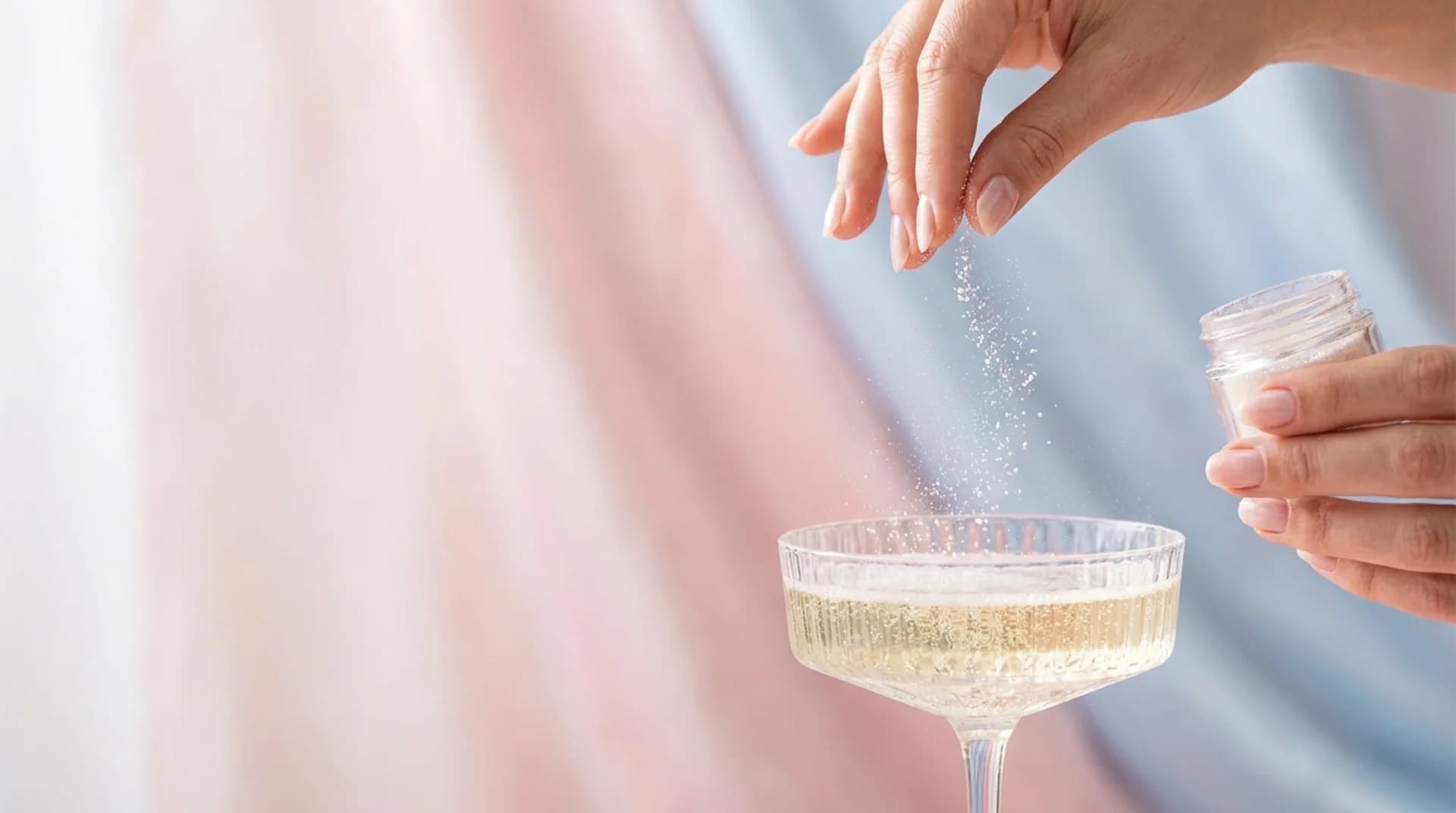 Une main saupoudre des paillettes au-dessus d’une coupe pétillante